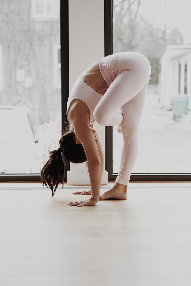 Female wearing white yoga gear doing yoga stretch.